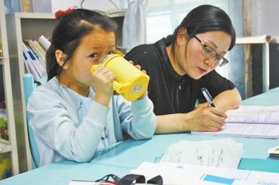 楊崇利老師在備課，孩子在身旁等待。