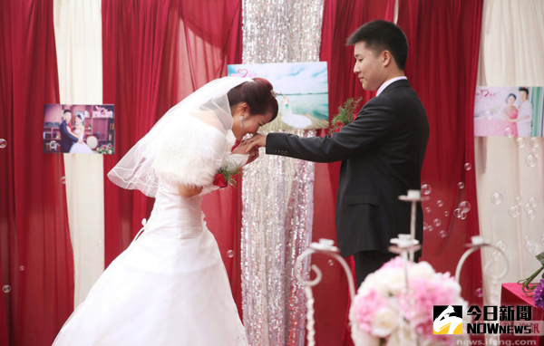 資料圖片：2015年2月16日，安徽省滁州市的一場婚禮上，新娘為新郎戴上婚戒，並獻上一吻。