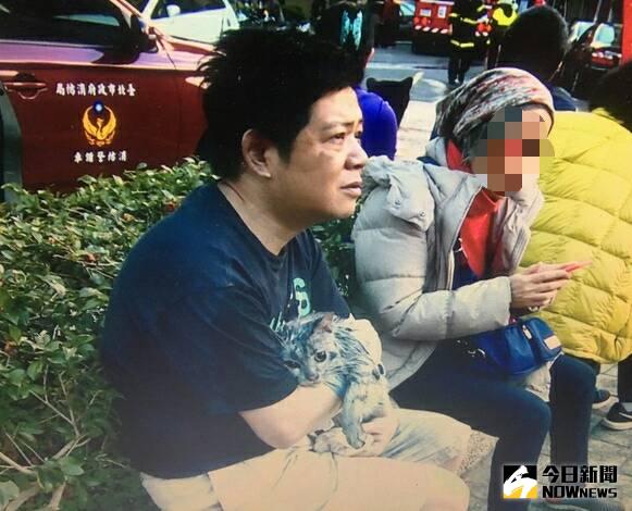 ▲台北馬偕醫院精神科醫師潘建志住家今(29)日失火，潘建志抱著愛貓坐在路邊。（圖／翻攝畫面）