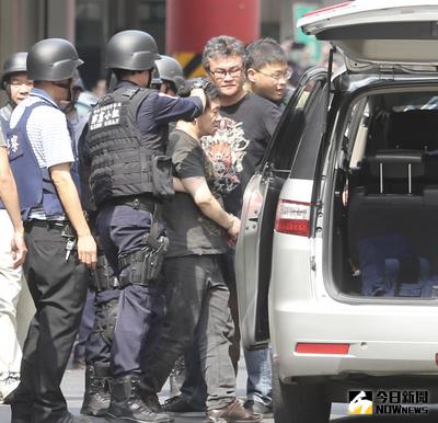 新北市中和興南觀光夜市30日發生警匪駁火案件，嫌犯劉邦誠（前右）躲進1處公寓與警方對峙逾3個小時，稍早劉嫌棄械投降，由警方帶回新店分局偵訊。中央社記者謝佳璋攝　106年4月30日