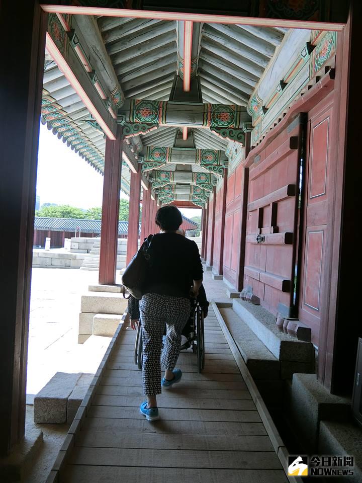 ▲韓國景福宮的古蹟中，擺放了木製斜坡，一位婦女推著輪椅上斜坡的背影。「克服障礙、奮發向上」，不是障礙者生命中的唯一。（圖／余秀芷提供）