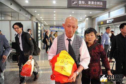 楊信璉抱著骨灰壇走出機場。