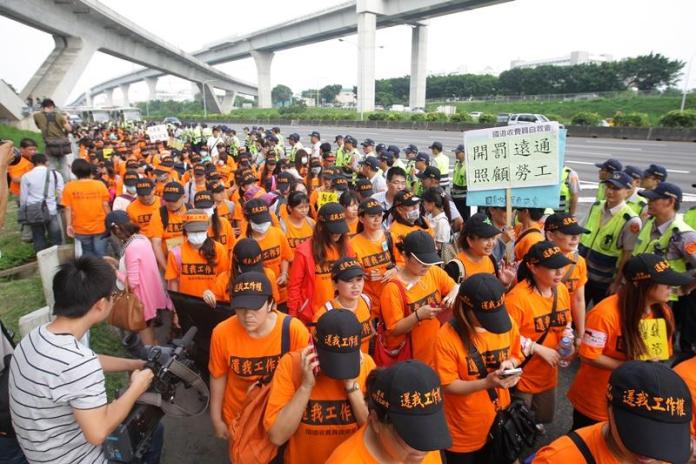 部分前國道收費員及勞工團體代表，103年6月13日到國道1號林口交流道舉牌抗議，高公局臨時局部封閉交流道。（中央社檔案照片）