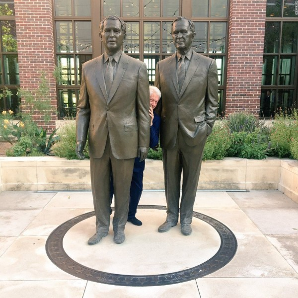 美國前總統被拍到躲在兩布希銅像中間探頭賊笑，相當逗趣。（圖／翻攝自推特）