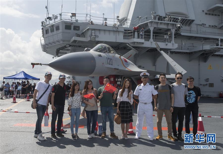 一群年輕人在遼寧艦的飛行甲板上與海軍士兵合影。