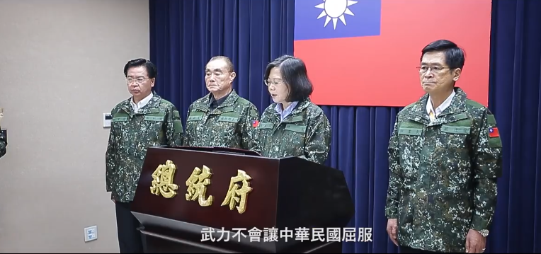 國防部日前公布2017政軍兵推影片，披露兵推最後階段，國安高層在指揮所模擬敵軍來襲，由總統蔡英文穿上現役軍用迷彩外套，發表告全國同胞書。不過，眼尖的網友發現，總統府秘書長吳釗燮與蔡英文迷彩服左臂上沒有國旗臂章，而其它國安高層迷彩服上都按軍中服誌規定，黏貼國旗臂章，因而引發議論。（圖／翻攝自國防部發言人臉書 , 2017.8.11）