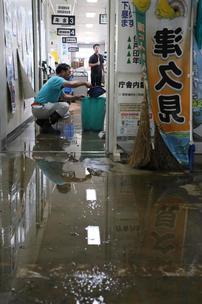 ▲泰利颱風肆虐日本，帶來強風豪雨，九州大分縣津久見市民眾清理辦公室所淹的積水。（圖／達志影像／美聯社）
