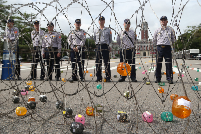 ▲「蔡政府欺騙人民選票！」在眾人怒吼下，400多隻小豬撲滿被丟向總統府，小豬撲滿從空中而降，一個個落在警方所圍起的禁區內，與遠方的總統府形成強烈對比。（圖／中央社）