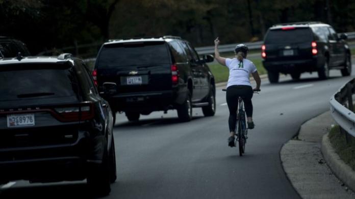 ▲今年十月底，美國一名騎乘自行車的婦人，經過川普車隊時豎起中指，照片被拍下後引起軒然大波，沒想到事後這名婦人竟遭公司開除。（圖／翻攝自CNN）
