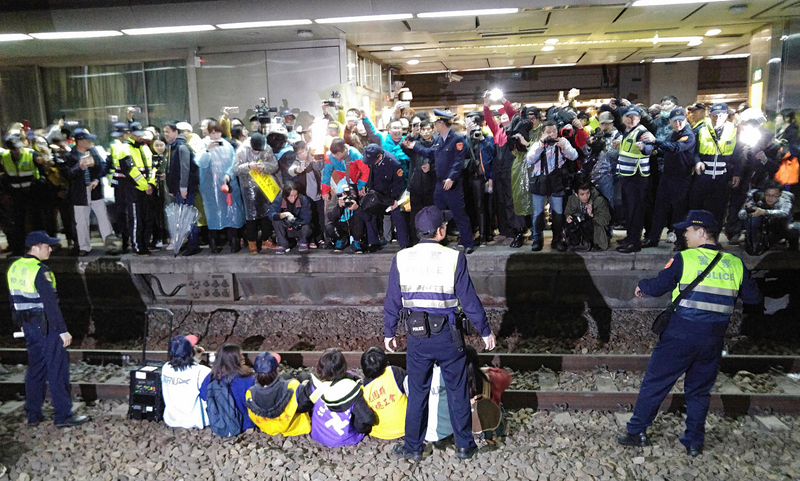 ▲反勞基法修法，桃園市產業總工會等勞團成員8日晚間發起到台北火車站臥軌抗爭，大批媒體到場關注，警方獲報到場處理。中央社記者施宗暉攝107年1月8日