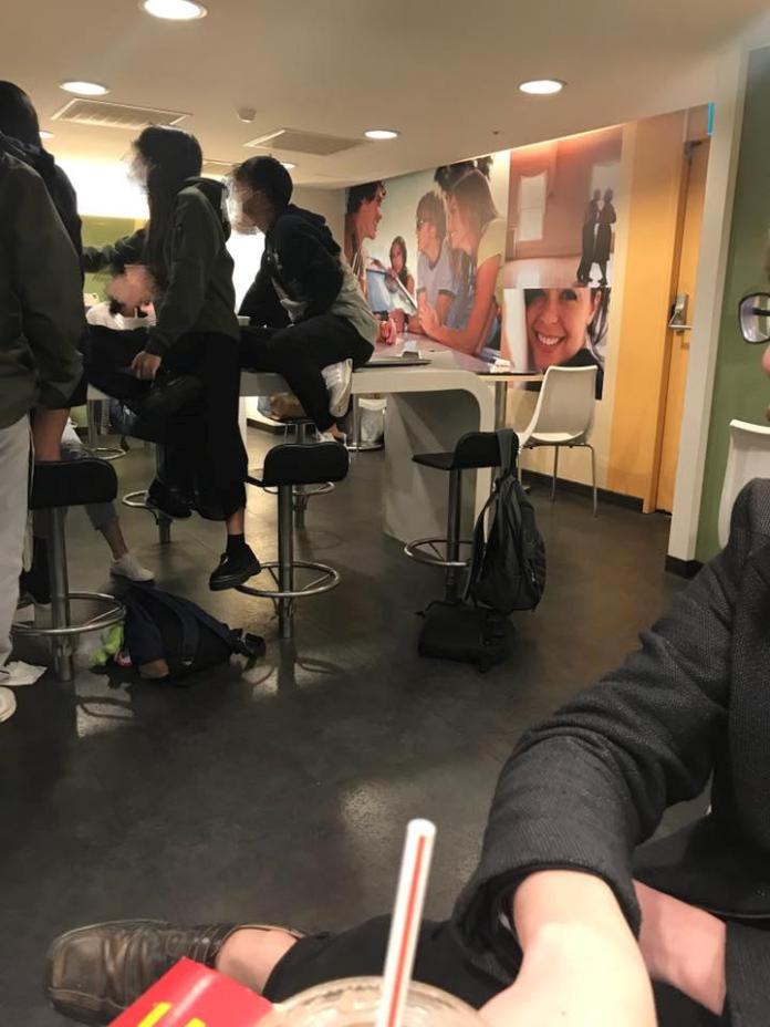 ▲學生在麥當勞用餐時一屁股直接坐在桌子上，腳還踩著椅子。（圖／翻攝自《爆料公社》）