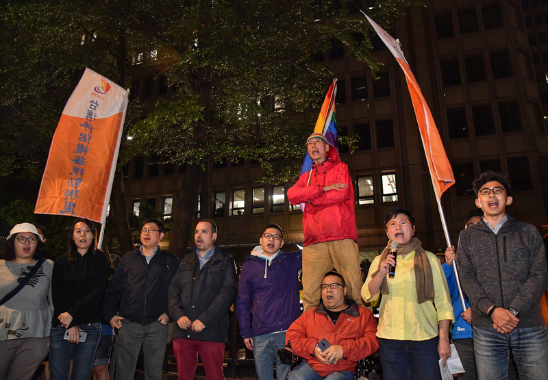 ▲同志運動先驅祁家威（紅衣者）與台灣伴侶權益推動聯盟等民團成員17日晚間到中選會前，抗議中選會通過反同公投提案，高呼「人權豈能公投」。中央社記者王飛華攝107年4月17日
