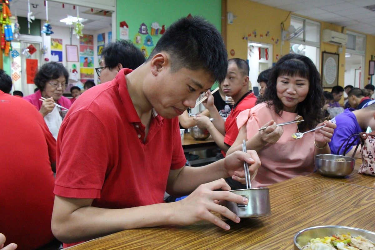 ▲慢飛天使品嘗母親們的愛心料理，用舌尖感受媽媽的味道。（圖／嘉愛啟智發展中心提供 , 2018.05.09）
