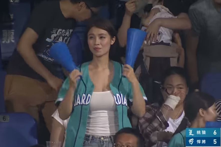 ▲女球迷在場上拿著加油棒為球員加油，被攝影機拍到時，她正好聳肩調整外套，胸前豪乳劇烈晃動，瞬間「震」暈不少男性球迷。（圖／翻攝自 YouTube ）