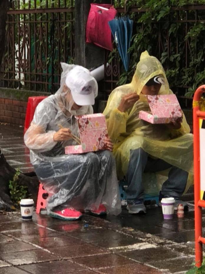 ▲一對退休夫妻在大雨中吃著便當，畫面看起來相當悲壯。（圖／翻攝自臉書「八百壯士捍衛權益」專頁）