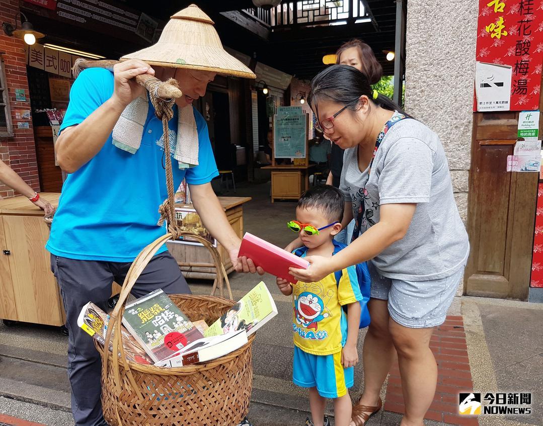 ▲深坑分館主任楊俊生肩挑書香扁擔於老街上漂書，向遊客推薦好書閱讀。（圖／記者蔡琇惠攝，2018.07.07）