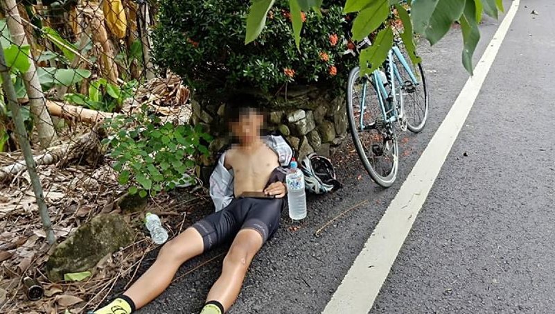 ▲一名騎腳踏車的弟弟疑因中暑暈倒，熱心的黑貓司機見狀趕緊上前將人移到陰涼處，並為他解開上衣、提供冰水協助降溫。（圖／翻攝自爆料公社 , 2018.07.21）