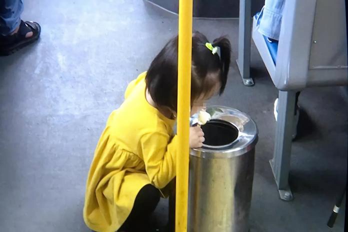 ▲大陸一名 2 歲小女孩蹲在公車垃圾桶旁吃冰棒，照片引起兩派網友論戰。（圖／翻攝自微博）