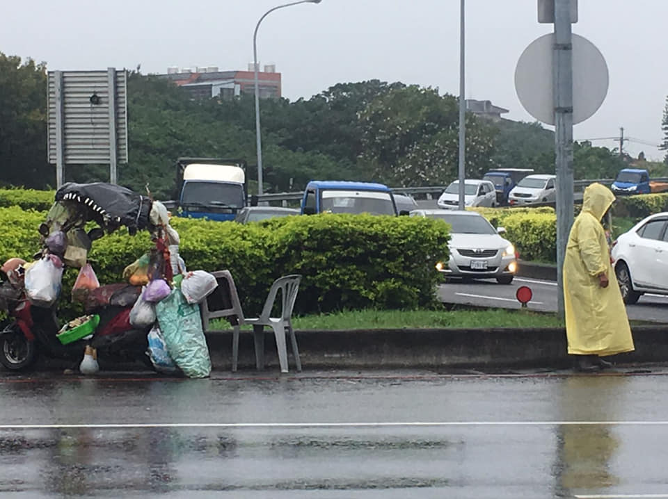 ▲好心網友行經1號國道中壢交流道時，發現一名老婆婆被一名白鬍男子(著黃色雨衣者)毆打，下車察看才發現男子因為老婆婆也想在交流道口賣玉蘭花而數度痛毆她。（圖／翻攝自「爆料公社」,2018.12.11）