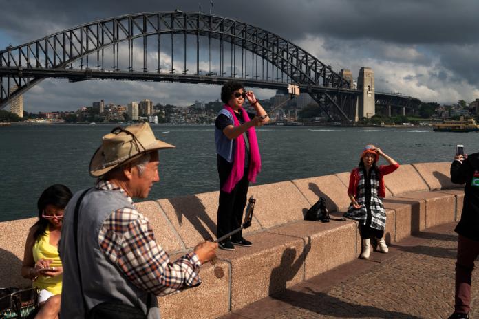 2018年赴澳洲旅遊陸客人數為142萬人次，消費額更佔整體海外旅客在澳開支27%。圖為一個陸客團在雪梨歌劇院及海港大橋前自拍，為了拍到滿意的照片，他們跑了七個地方。（圖／翻攝紐約時報）