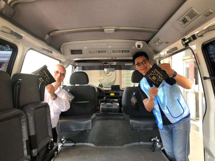 黃志中局長（左）與李政憲總幹事（右）準備將菱炭包掛在復康巴士上