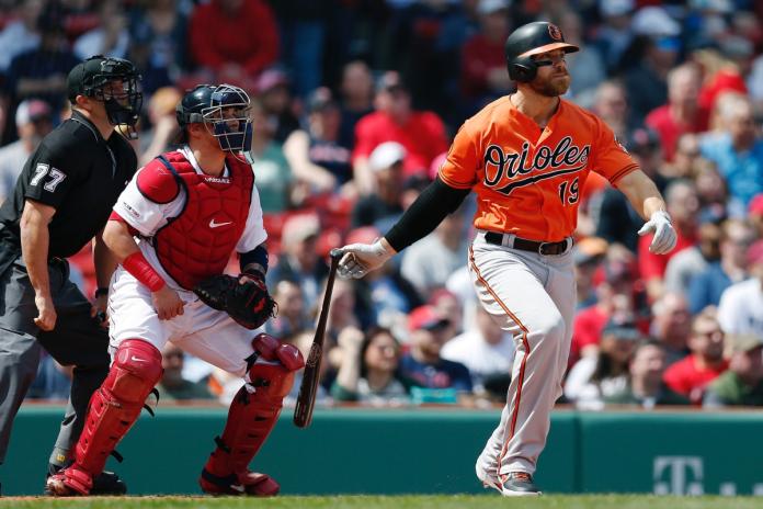 Baltimore Orioles' Chris Davis watches his two-run single in front of Boston Red Sox's Christian Vazquez during the first inning of a baseball game in Boston, Saturday, April 13, 2019. (AP Photo/Michael Dwyer)