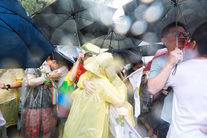 同志伴侶冒著大雨堅守青島東路，稍早關鍵條文二、四條獲通過，台灣如願成為亞洲第一個同婚合法化國家，現場同志喜極而泣。（圖／記者葉政勳攝）