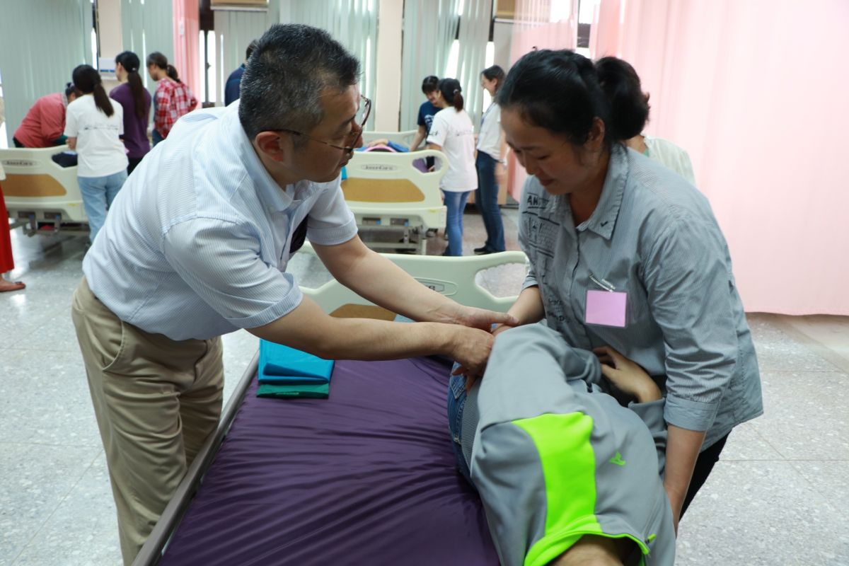 ▲日本老師印南裕之（左）指導學員將病患翻身及協助下床。（圖/吳鳳科大提供）