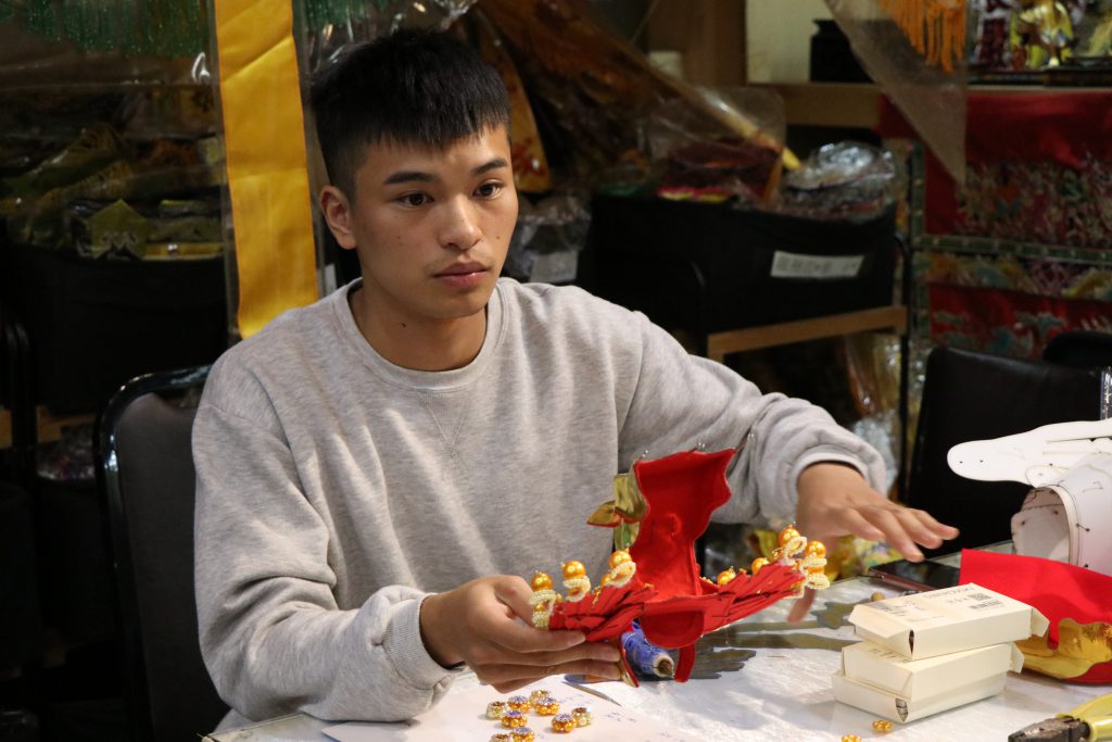 23歲的潘家齊長期為神明服務，問事時擔任太子爺的乩身，平時則於店內製作神明服裝、飾品。　（初聲／高海葳攝）