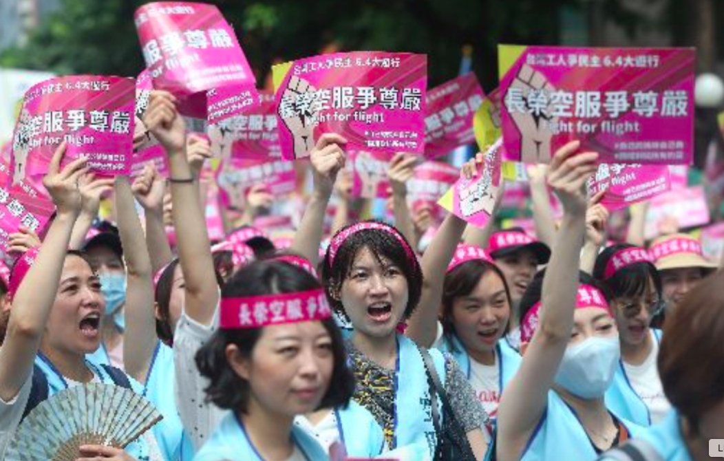 ▲長榮空服員發動罷工，身穿藍背心、頭繫粉色布條，要求資方聽見勞方聲音。（圖／中央社）