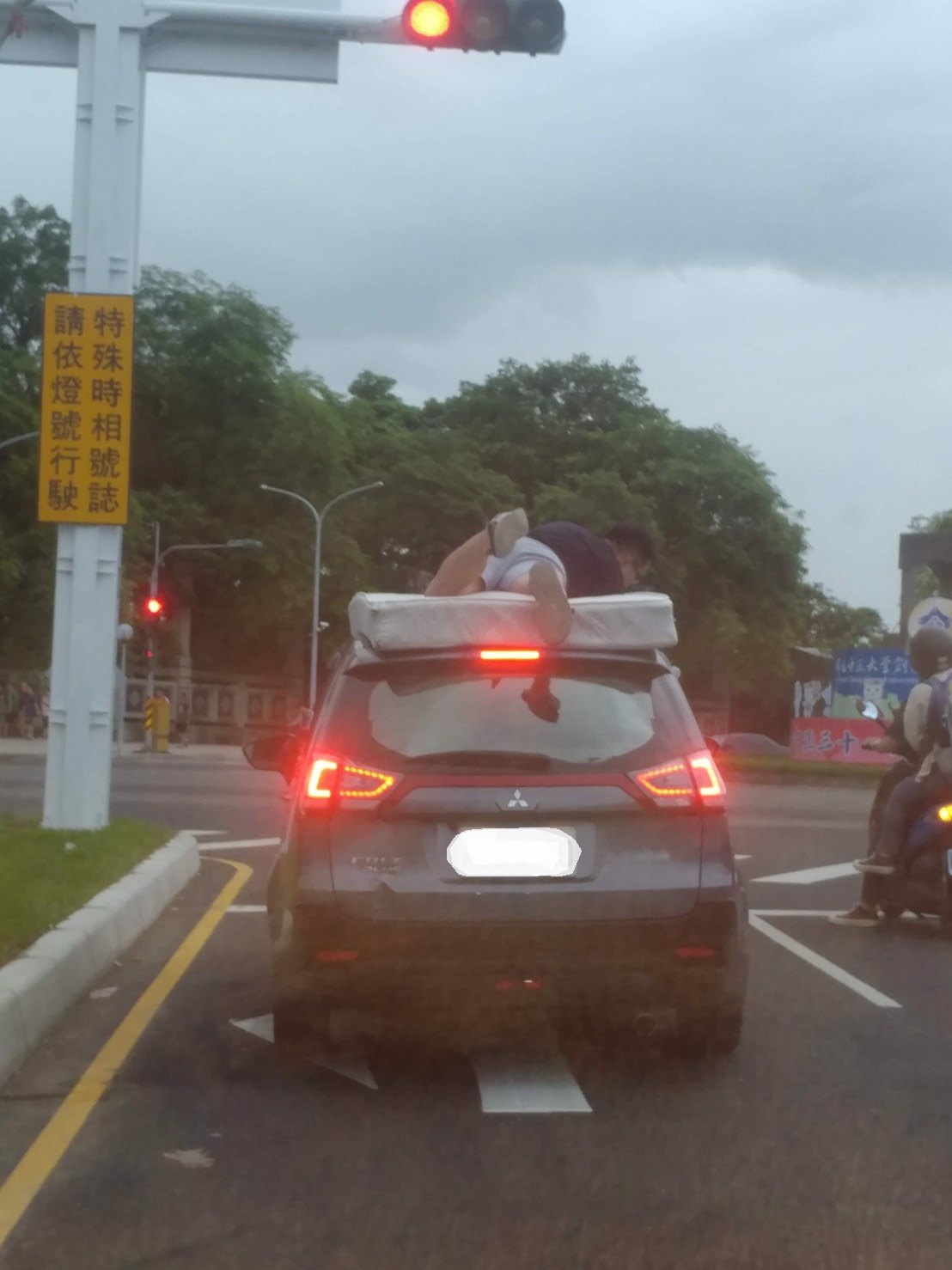 三寶學生搬家上路，床墊車頂載，上面再趴個人壓頂，完全無防護固定措施，驚呆用路人。（圖/記者邱嘉琪翻攝，2019.06.26）