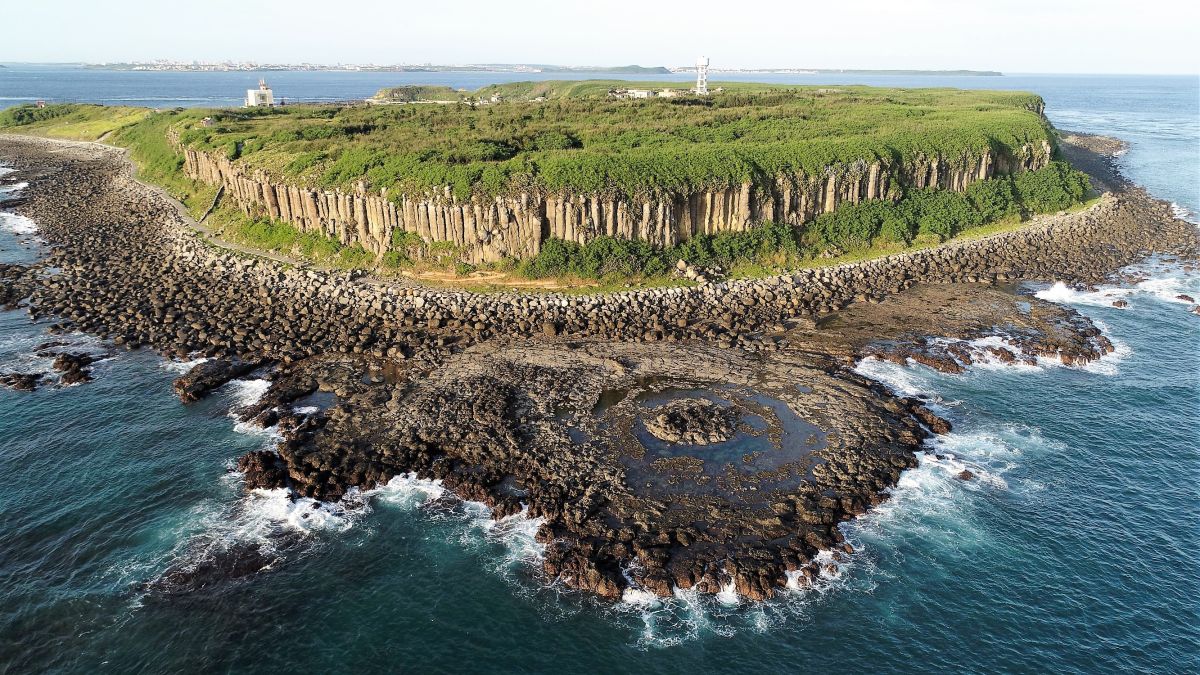 ▲澎湖的玄武岩是經過多次火山活動，熔岩從淺海或地下裂隙湧出地面，冷卻後堆積而成。熔岩流冷卻之後非常容易成為垂直的柱狀節理。圖為桶盤蓮花池空拍照。（圖／郭偉民提供，2019.07.18）
