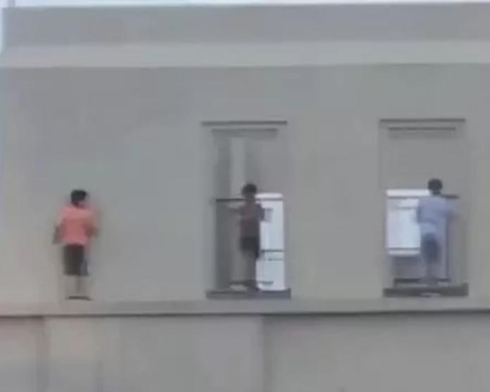 ▲3名男童爬出34樓頂樓欄杆，在牆邊外沿移動。（圖／截自YouTube影片）