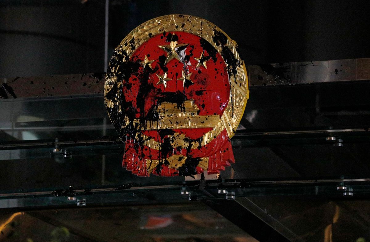 ▲香港反送中人士21日到西環中聯辦附近，向中聯辦國徽投擲黑色油漆彈。（圖／美聯社／達志影像）