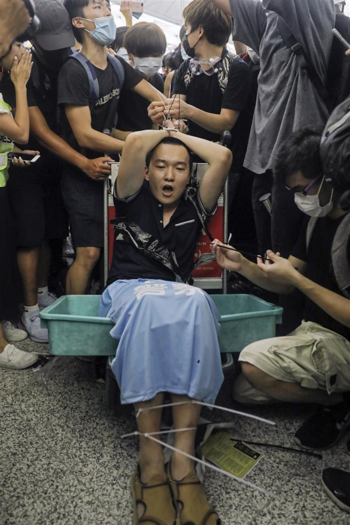 ▲環球時報記者付國豪被示威者用索帶綁在機場行李車上。（圖／翻攝網路）