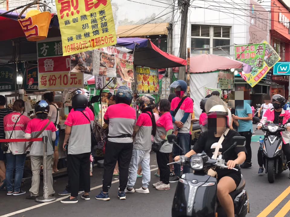 ▲ 19 日一名網友在臉書社團「爆廢公社」分享一張照片，畫面中 10 名身著桃紅色上衣的外送員，圍繞在攤位旁，讓網友百思不解，貼文釣出當地人出面解惑。（圖／翻攝自爆廢公社）