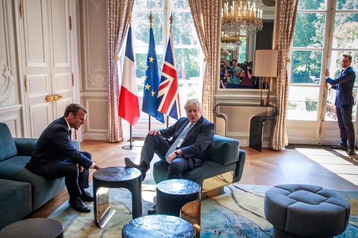 ▲英國首相強生昨天與法國總統馬克宏會面時，一張照片顯示，強生把腳擱在艾里賽宮一張桌子上，因而被貼上「無禮」和「使人難堪」標籤，但事實上，此舉只是回應馬克宏一個玩笑。（圖／美聯社／達志影像）