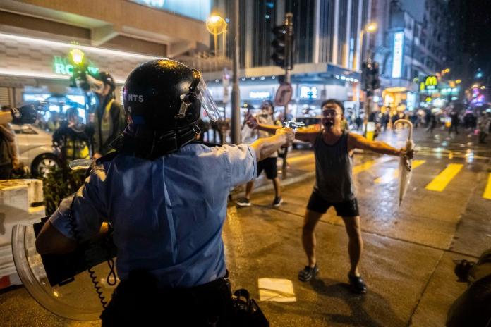 ▲今（26）日在美國網路論壇 Reddit 上則有網友 PO 出了一張照片，只見照片中一位香港大叔手持雨傘，擋在持槍的警察和民眾之間，畫面令人震撼。（圖／翻攝自 Reddit）
