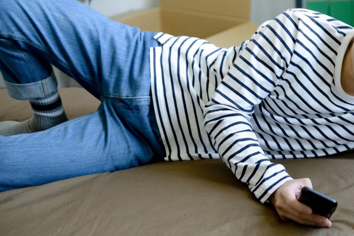 ▲因為疫情關係許多人待在家時間變長，喜歡在床上用手機一整天，長久下來開始造成背部疼痛的疾病。（示意圖，非當事人／取自 photoAC ）