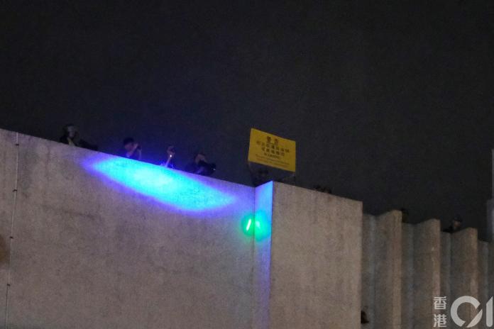 ▲ 6 日晚間有人在九龍東駐港解放軍軍營高舉黃旗，警告示威者。（圖／翻攝自香港 01 ）