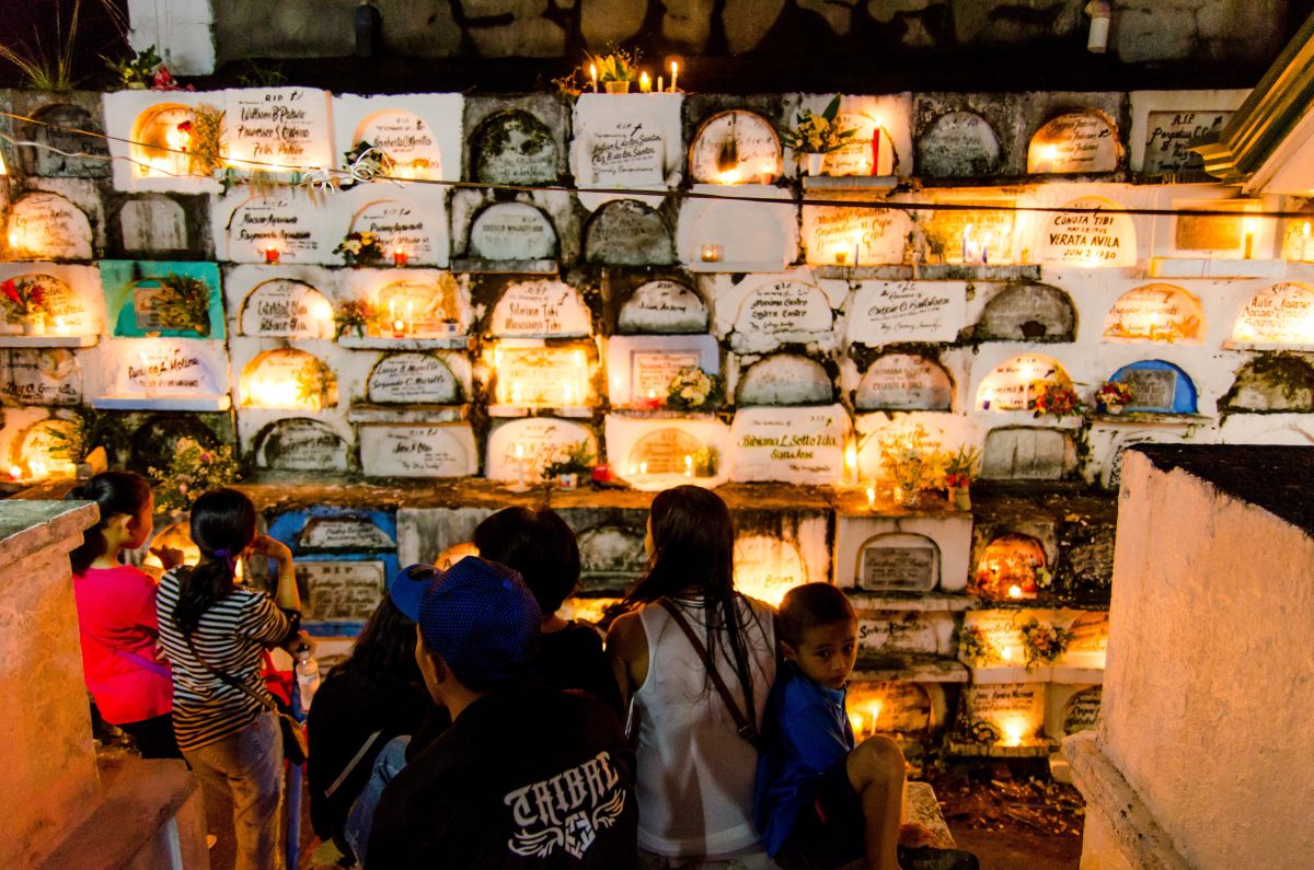 家族群聚清掃墳墓周圍，夜晚在馬尼拉、棉蘭老島（Mindanao）等城市墓園的墳前野餐聚會、載歌載舞，成為各國觀光客前往參觀的另類文化之旅。（圖／ shutterstock）