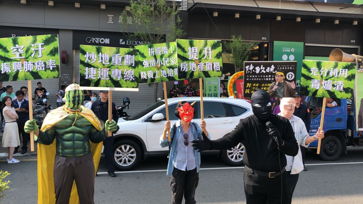 ▲立委參選人陳致曉扮成柯南黑衣人，帶著西瓜俠至林俊憲競選總部前演講。（圖／陳聖璋攝，2019.11.01）