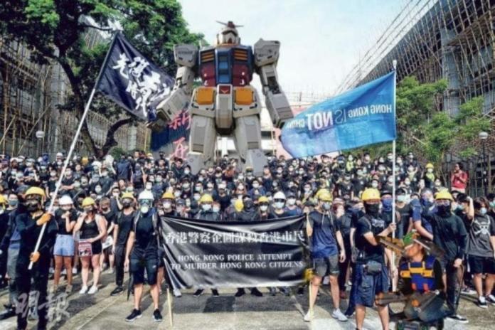 ▲有香港網友藉著修圖軟體，惡搞出機動戰士鋼彈站在示威者後方的照片。（圖／翻攝自明報）