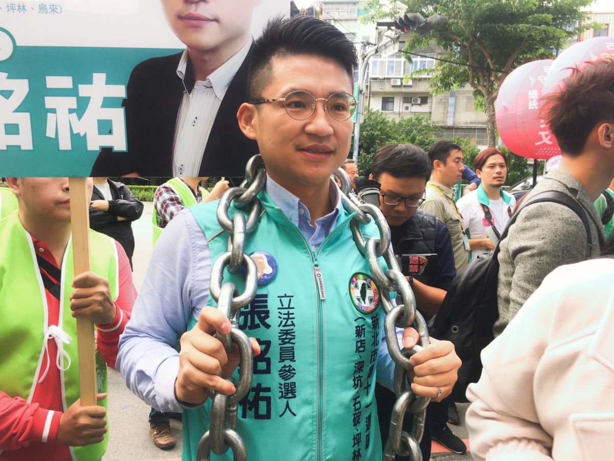 ▲新北市第11選區參選人張銘祐揹著10公斤鐵鍊現身，強調自己選區是艱困選區，揹著鐵鍊象徵要突破困境。（圖／記者陳志仁攝，2019.11.18）