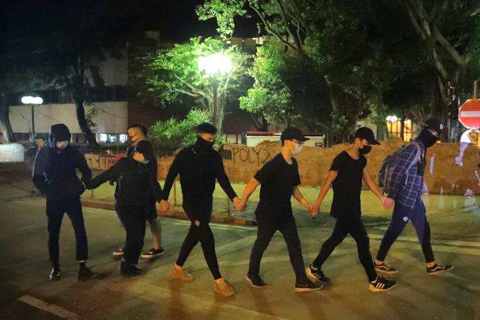 ▲香港理工大學21日凌晨有6人離開校園，在防暴警察監視下進入附近的救護站。（圖／美聯社／達志影像）