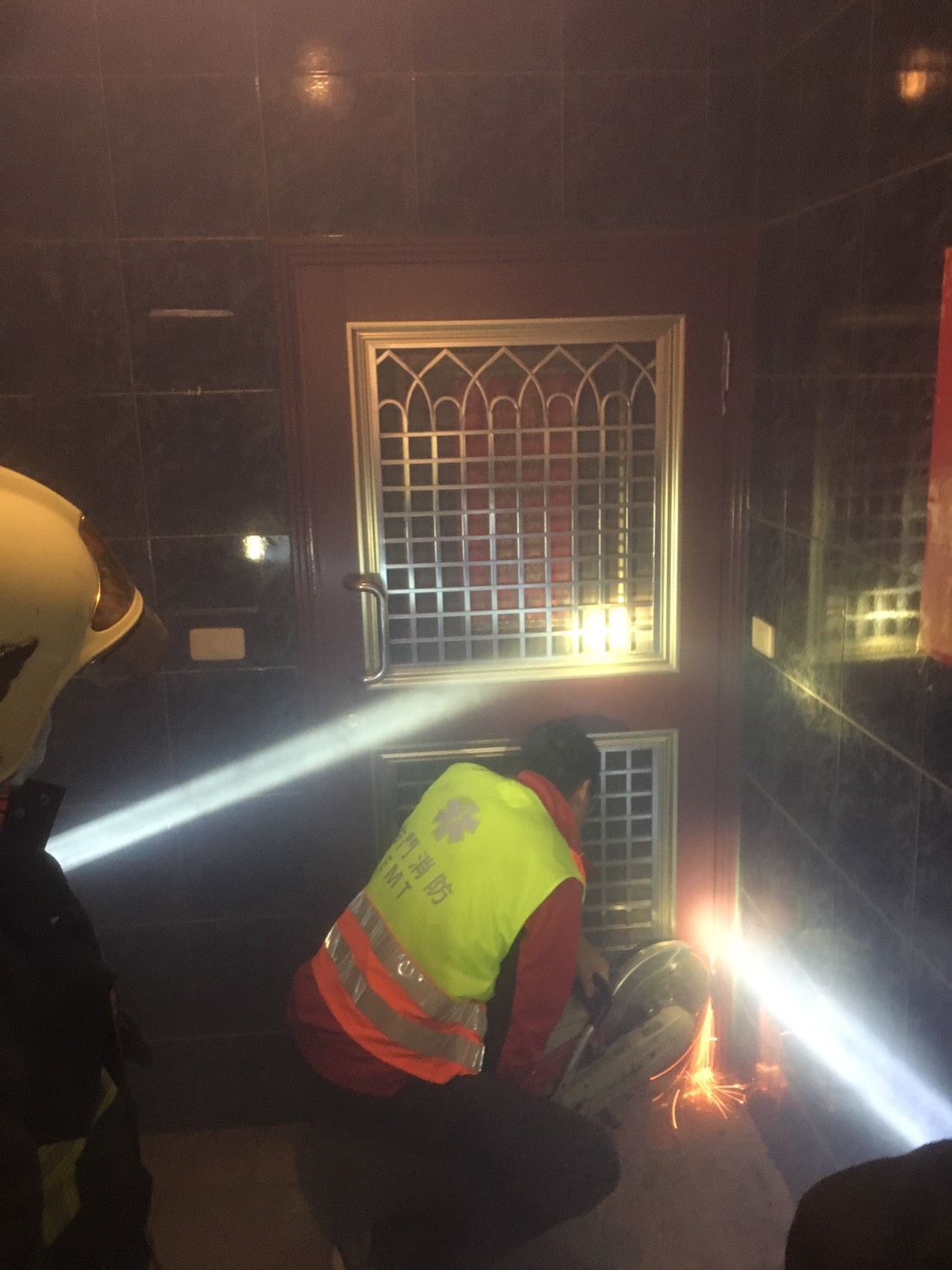 ▲王姓男子疑身體不適受困家中，金城消防分隊以圓盤鋸破門，現場花火四濺。（圖／金門消防局提供）