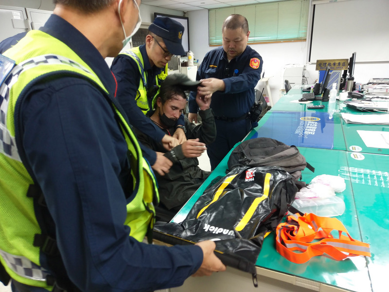 一名外籍男子（坐者）2日下午闖入桃園機場跑道，更爬上正準備起飛的中華航空CI-28班機起落架，導致航班延誤起飛，航警獲報到場將人帶回訊問。（翻攝畫面）中央社記者吳睿騏傳真108年11月2日