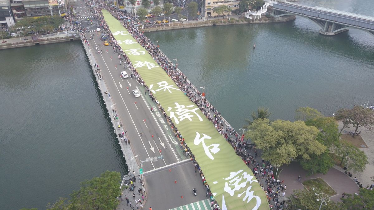 ▲「Wecare高雄」、「公民割草行動」等罷韓團體舉行「罷韓大遊行」，群眾們拉著「保衛台灣」的綠色大旗，場面壯觀。(圖／Wecare高雄提供)