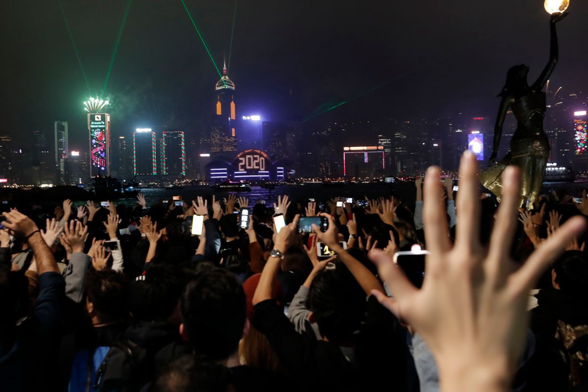 ▲部分港民觀賞跨年燈光秀時，比出「五大訴求，缺一不可」的手勢，象徵來年繼續抗爭的決心。（圖／美聯社／達志影像）