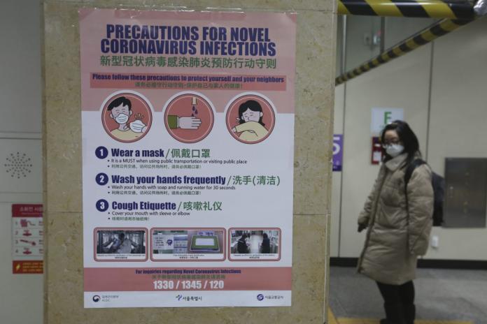 一名女子在南韓首爾的地鐵站經過一張預防新型冠狀病毒的宣導海報。圖片攝於2020年2月6日。（圖片由美聯社提供）